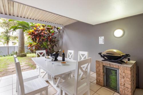 a white dining room with a white table and chairs at Ocean Villa in Durban