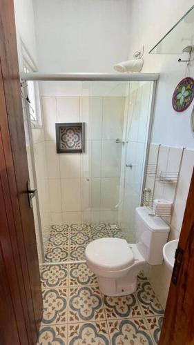 a bathroom with a toilet and a glass shower at Chalé Arcos do Sol - Carrancas in Carrancas