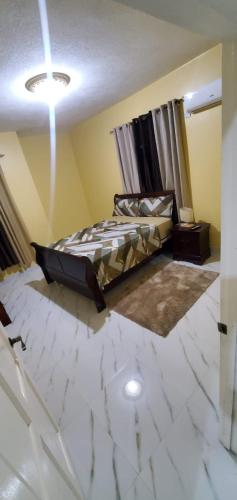 sypialnia z łóżkiem i białą podłogą wyłożoną kafelkami w obiekcie Finest Accommodation #528 Stem Ave Jacaranda 1 bedroom w mieście Spanish Town