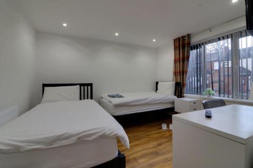 Habitación blanca con 2 camas y ventana en Tarleton house en Stoke on Trent