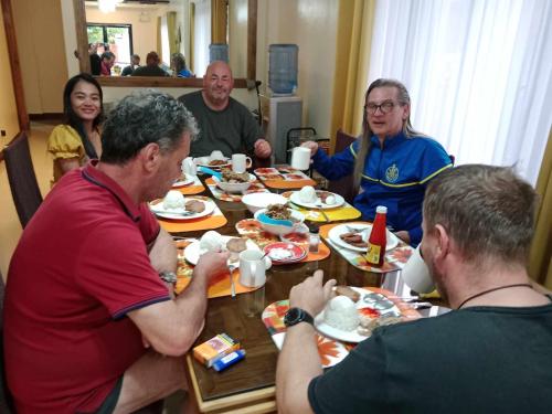 Eine Gruppe von Menschen, die an einem Tisch sitzen und Essen essen. in der Unterkunft Villa Cresenciana in Batuan
