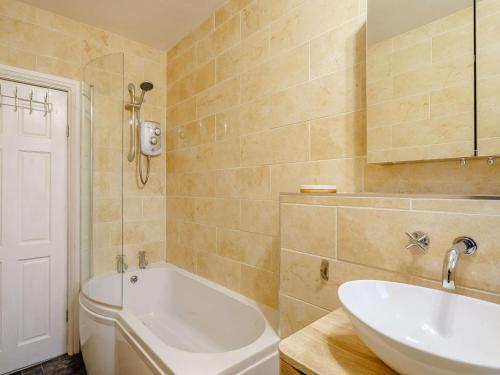ein Badezimmer mit einer weißen Badewanne und einem Waschbecken in der Unterkunft 4 Bed in Broughton - in - Furness 90412 in Duddon