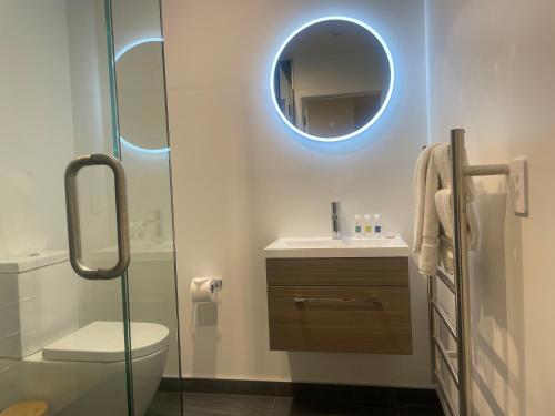 bagno con servizi igienici, lavandino e specchio di Alpine Junction Townhouse Apartments, Lodge & Hotel a Wanaka