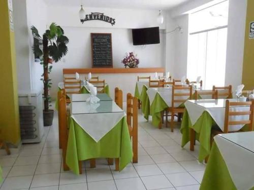 タクナにあるCASA REAL HOTELのテーブルと椅子(緑のテーブルクロス付)が備わるレストラン