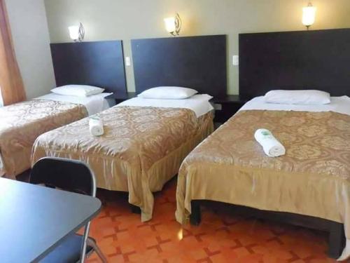 タクナにあるCASA REAL HOTELのベッド2台とテーブルが備わるホテルルームです。