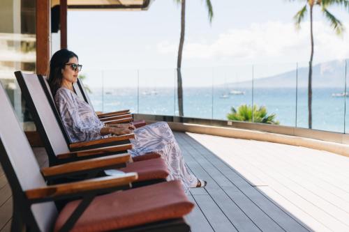 a woman sitting on a bench with a pile of books at Sheraton Maui Resort & Spa in Lahaina