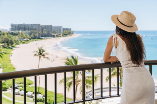 a woman standing on a balcony looking at the beach at Sheraton Maui Resort & Spa in Lahaina