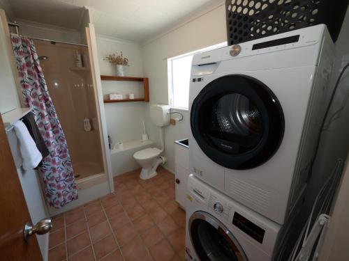 a washing machine in a bathroom with a toilet at Fun in the Sun in Cable Bay