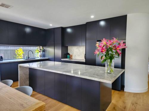 a kitchen with a large counter with a vase of flowers at Luxurious, Entertainers Delight! in Safety Beach