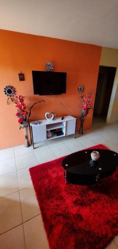 a living room with a red rug and a flat screen tv at Finest Accommodation Seville Meadows 2 bedroom in Spanish Town