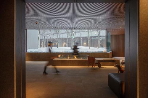 a person walking through a room with a large window at MUWA NISEKO in Kutchan