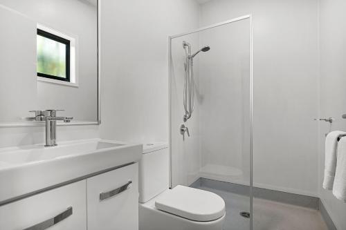 a white bathroom with a toilet and a shower at Kipara Tropical Rainforest Retreat in Airlie Beach