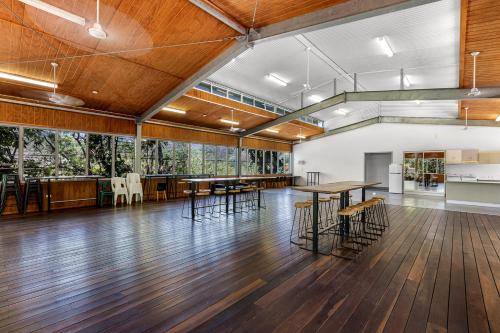 a large room with wooden floors and tables and chairs at Kipara Tropical Rainforest Retreat in Airlie Beach