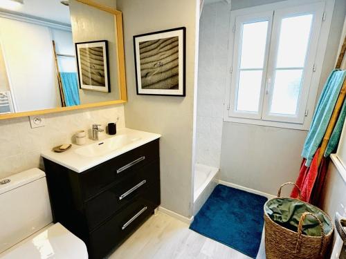 ein Badezimmer mit einem Waschbecken, einem Spiegel und einer Badewanne in der Unterkunft Maison Saint-Clément-des-Baleines, 4 pièces, 6 personnes - FR-1-258-128 in Saint-Clément-des-Baleines