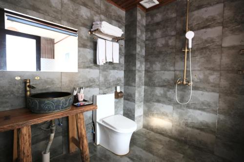 Yangshuo Xiao Long River Hotel في يانغتشو: حمام مع مرحاض ومغسلة ودش
