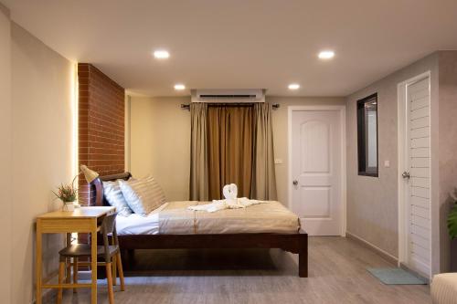 a bedroom with a bed and a table with a stool at Gate78 Hostel Maephim Beach in Mae Pim