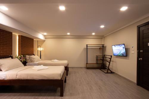 a hotel room with two beds and a flat screen tv at Gate78 Hostel Maephim Beach in Mae Pim