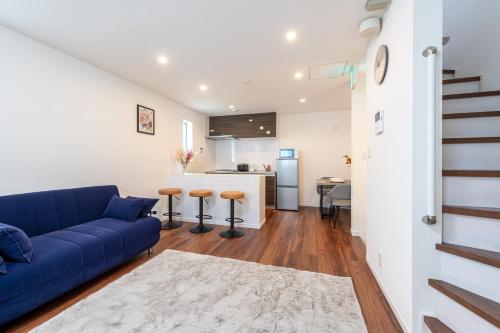 a living room with a blue couch and a kitchen at 千駄木戸建 in Tokyo