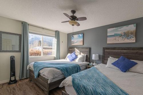 1 Schlafzimmer mit 2 Betten und einem Deckenventilator in der Unterkunft B211 MTN View ground floor town house- 2BD, Sleeps 8, hot tub, free parking, close to Banff in Canmore