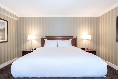 a large white bed in a room with two lamps at Sandman Signature Edmonton Downtown Hotel in Edmonton