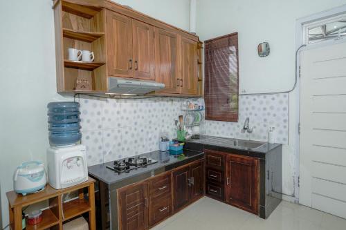 a kitchen with wooden cabinets and a stove top oven at Sekar Gambir Homestay in Batu