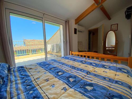 een slaapkamer met een bed en een groot raam bij Maison Gruissan, 3 pièces, 5 personnes - FR-1-229-877 in Gruissan