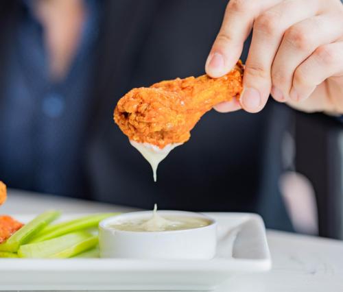 a person holding a piece of food with a dipping sauce at voco Niagara Falls - The Cadence by IHG in Niagara Falls