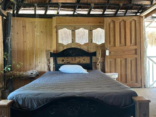 1 dormitorio con 1 cama grande y paredes de madera en Punta Arena EcoHostal & EcoFit, en Playa Punta Arena