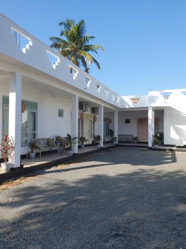 a large white building with a palm tree behind it at GypSea Madiha in Madihe East