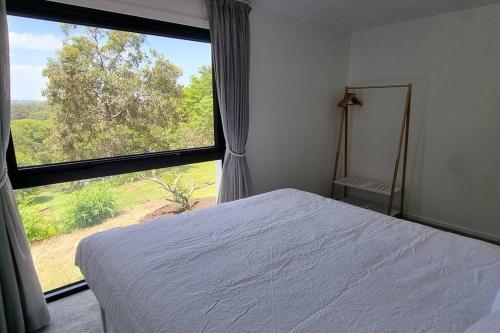 1 dormitorio con cama y ventana grande en Serenity View Studio Retreat en Woombye