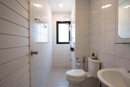 a white bathroom with a toilet and a sink at Gate78 Hostel Maephim Beach in Mae Pim