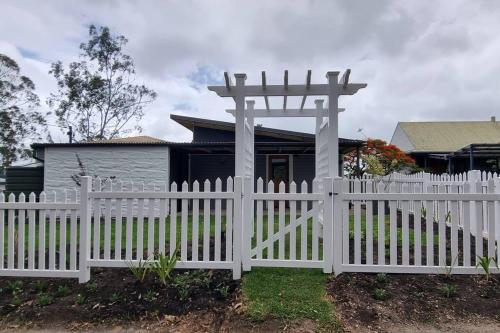 a white fence in front of a house with a gazebo at Serenity View Studio Retreat in Woombye