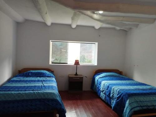 a bedroom with two beds and a window at Casa Corazao in Urubamba