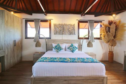 a bedroom with a large white bed with blue pillows at Villa Lebah - Tranquil Paradise of 3 bedroom Heart of Seminyak in Seminyak