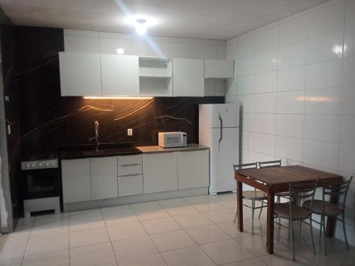a kitchen with a table and a white refrigerator at Casa em Mongaguá, próximo a Plataforma de Pesca in Mongaguá