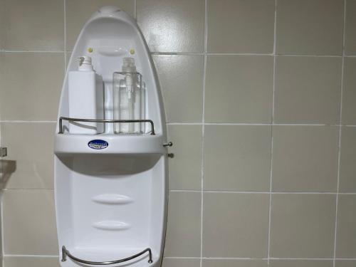a white soap dispenser in a tiled bathroom at Country Complex Bangna in Bangkok