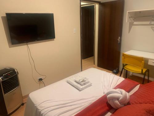 a bedroom with a bed with a flat screen tv on the wall at Quarto área central zona 04 in Maringá