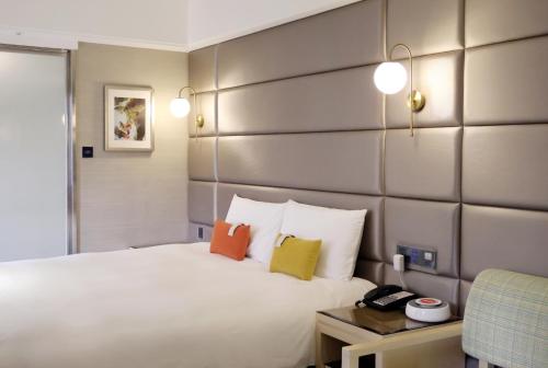 sypialnia z białym łóżkiem i kolorowymi poduszkami w obiekcie Olah Poshtel Taichung Wenxin w mieście Taizhong