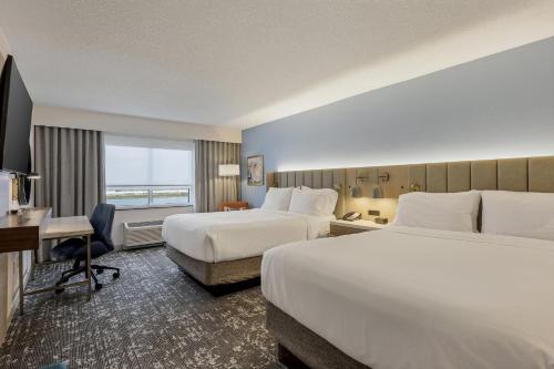 a hotel room with two beds and a desk at Crowne Plaza Ft Myers Gulf Coast by IHG in Fort Myers