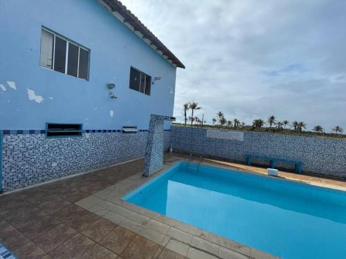 a blue swimming pool next to a house at Duplex em condomínio / Guriri ES in São Mateus