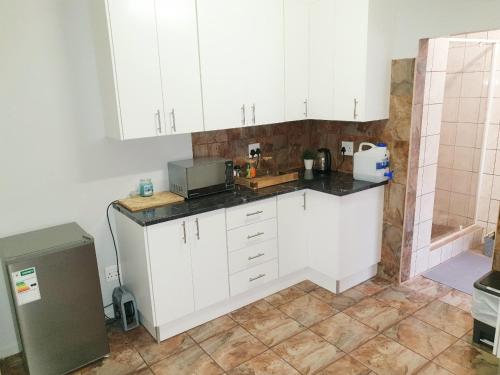 a kitchen with white cabinets and a sink at Rooibok 4 in Kathu