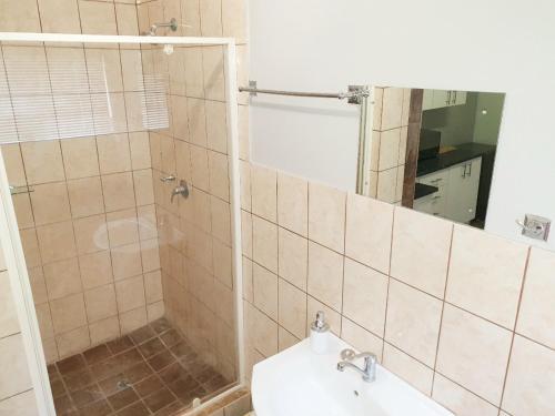 W łazience znajduje się prysznic, umywalka i lustro. w obiekcie Rooibok 4 w Kathu