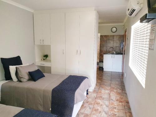 a bedroom with a bed and a kitchen at Rooibok 4 in Kathu