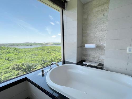 a bath tub in a bathroom with a large window at Shima Kanko Hotel The Bay Suites in Shima