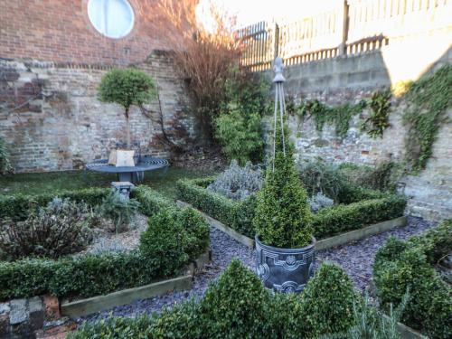 a garden with a table and some plants and a wall at The Old Clock Makers in Ashbourne