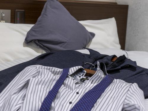 a pile of clothes and a blue tie on a bed at Hotel New Gaea Domemae in Fukuoka