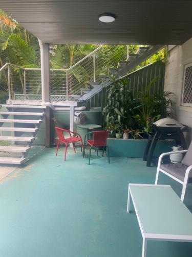 a patio with red chairs and a table and stairs at Central Oasis in Coffs Harbour
