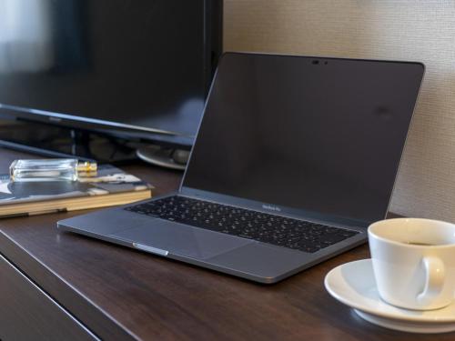 a laptop computer sitting on a desk with a cup of coffee at Hotel New Gaea Domemae in Fukuoka