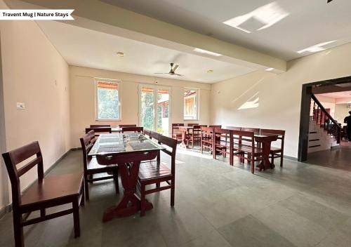 uma grande sala de jantar com mesas e cadeiras de madeira em Pepper Corn Retreat by Travent Mug em Sakleshpur