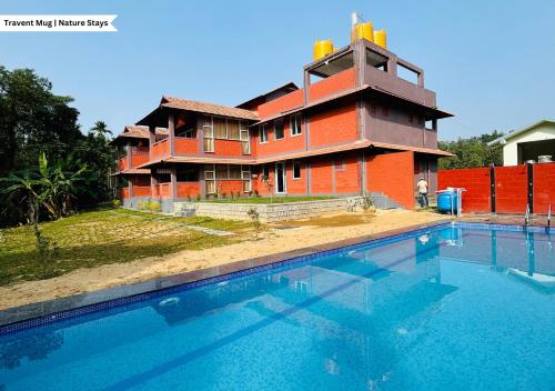 a house with a swimming pool in front of it at Pepper Corn Retreat by Travent Mug in Sakleshpur